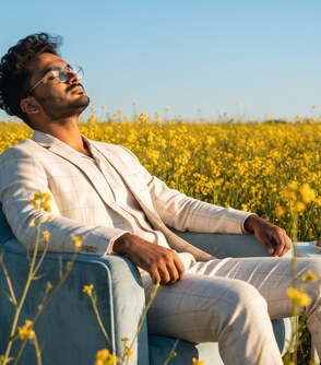 Yash Gandhi seated in a field of yellow flowers