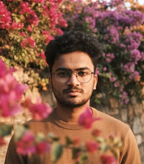 Yash Gandhi portrait with pink flowers behind him