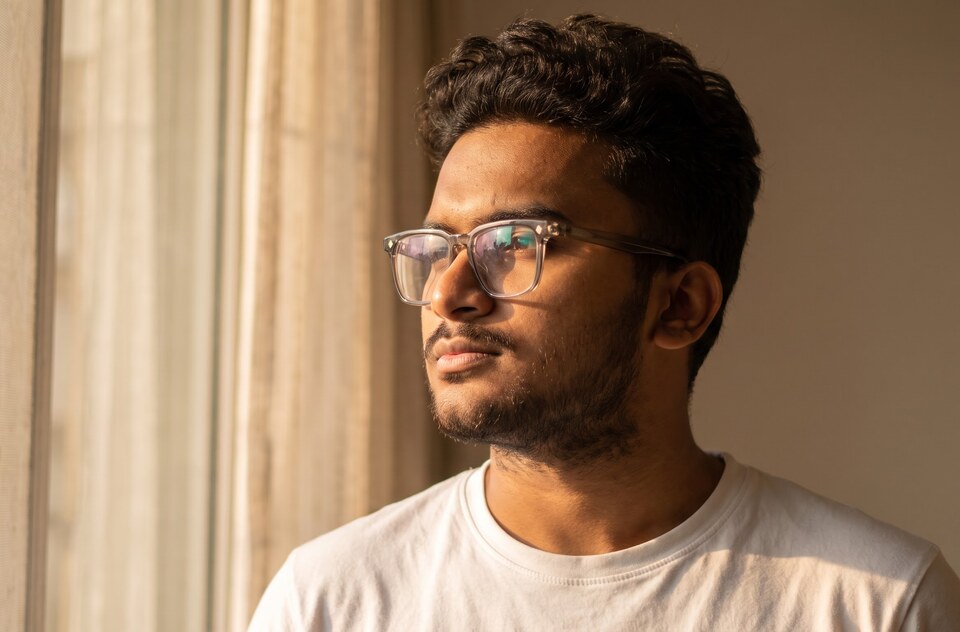 Yash Gandhi looking out of a window in soft golden light